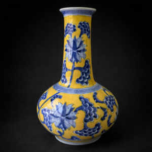 Florero de porcelana esmaltada azul sobre fondo amarillo.
