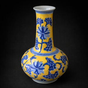 Florero de porcelana esmaltada azul sobre fondo amarillo.