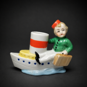 Figura alemana de niño en barco de porcelana, ca. 1950.