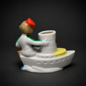 Figura alemana de niño en barco de porcelana, ca. 1950.