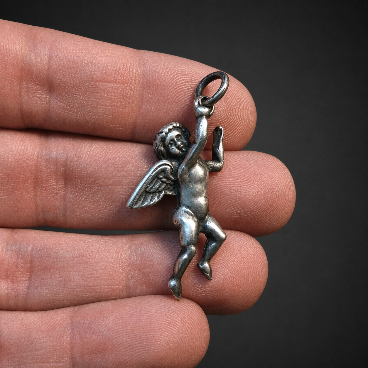 Dije de querubín alado en plata, ca. 1950. Dije de querubín alado en plata, ca. 1950.